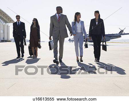 Stock Photography - Five businesspeople walking at airport. Fotosearch