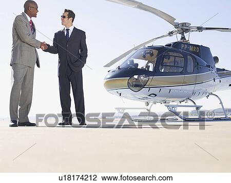 Two businessmen shaking hands near helicopter (low angle view) View Large Photo Image Stock Image - Two businessmen shaking hands near helicopter (low angle view). Fotosearch
