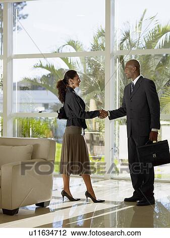 Stock Image - Two businesspeople shaking hands. Fotosearch
