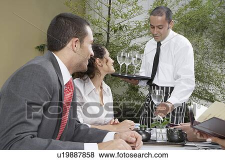Waiter serving water for businesspeople View Large Photo Image Stock Photo - Waiter serving water for businesspeople. Fotosearch
