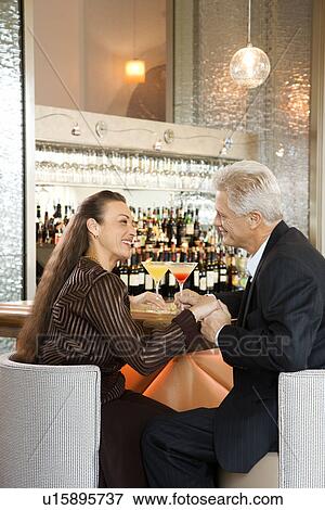 Caucasian mature adult male and prime adult female sitting at bar holding hands. View Large Photo Image Stock Photo - Caucasian mature adult male and prime adult female sitting at bar holding hands.. Fotosearch