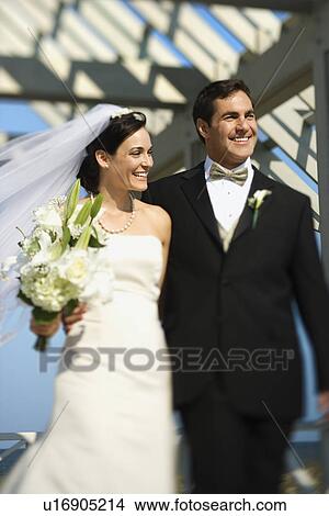 Picture - Caucasian mid-adult bride and groom walking together smiling.. Fotosearch