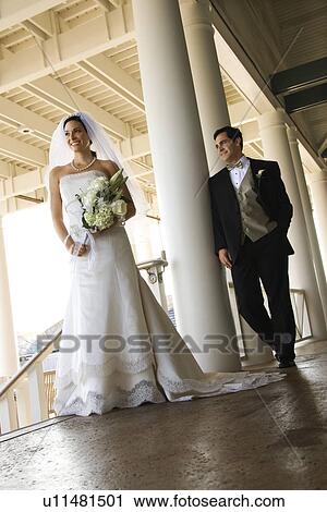 Stock Image - Caucasian mid-adult fbride and groom standing on porch.. Fotosearch