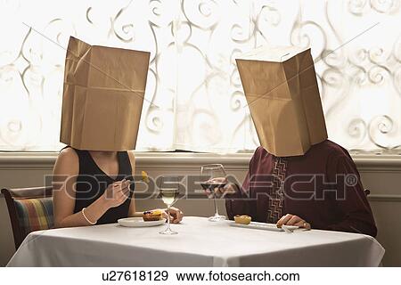 Stock Photo - Couple dining in a restaurant with paper bags over heads. Fotosearch