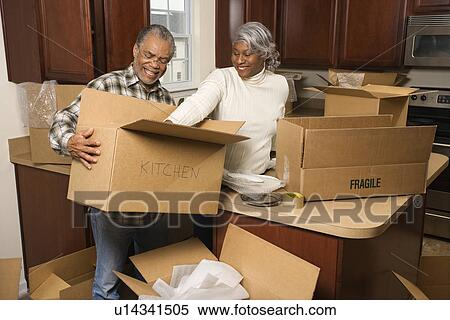Couple packing moving boxes in kitchen View Large Photo Image Stock Photography - Couple packing moving boxes in kitchen. Fotosearch
