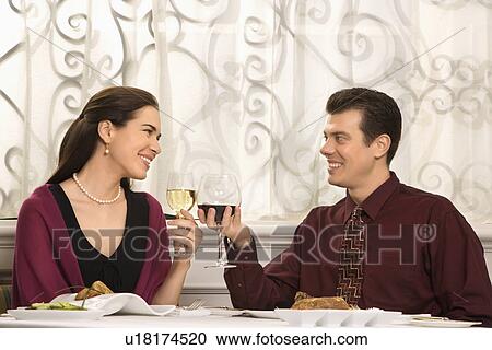 Couple smiling and toasting wine glasses in restaurant View Large Photo Image Stock Image - Couple smiling and toasting wine glasses in restaurant. Fotosearch