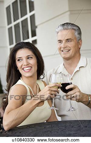 Stock Image - Couple toasting sitting at table. Fotosearch