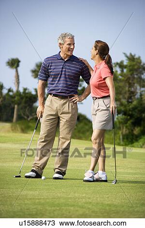 Man and woman standing on golf course talking to each other View Large Photo Image Stock Image - Man and woman standing on golf course talking to each other. Fotosearch