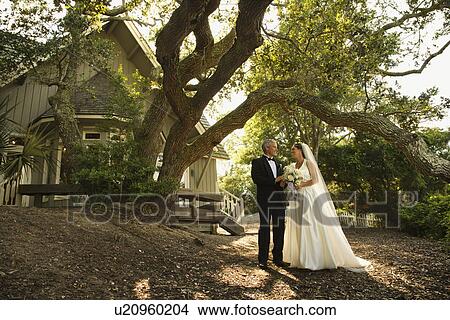 Mid-adult bride and groom standing outside of church. View Large Photo Image Picture - Mid-adult bride and groom standing outside of church.. Fotosearch