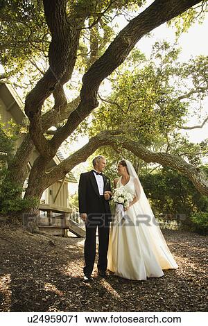 Stock Image - Mid-adult bride and groom standing outside of church.. Fotosearch