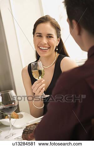 Stock Image - Mid adult couple smiling and drinking wine and dining. Fotosearch