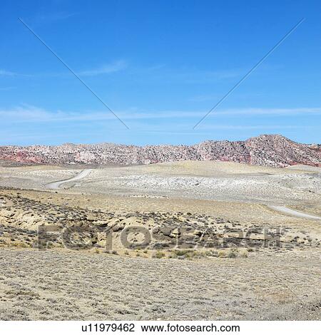 Stock Image - Desert land with rocky cliffs in background of Cottonwood Canyon. Fotosearch