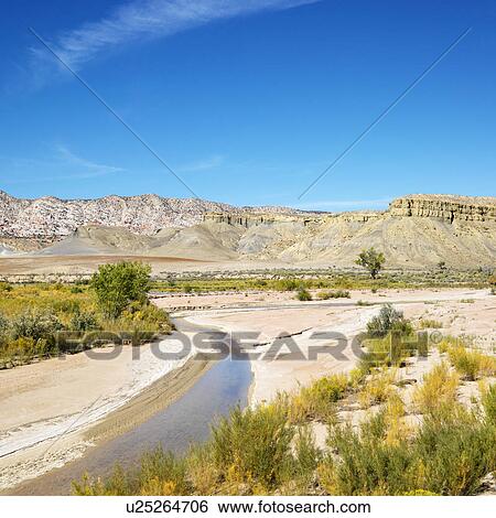 Small stream running through desert with rocky cliffs in background in Cottonwood Canyon, Utah. View Large Photo Image Stock Photograph - Small stream running through desert with rocky cliffs in background in Cottonwood Canyon, Utah.. Fotosearch