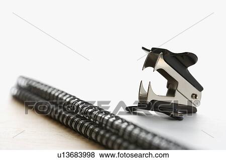 Stock Photo - Black staple remover on top of a spiral bound notebook. Fotosearch