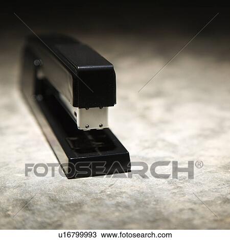 Stock Image - Black stapler on textured background. Fotosearch