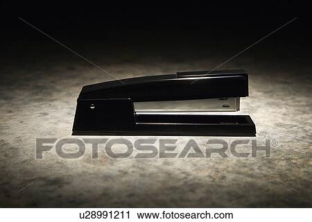 Stock Image - Black stapler with black vignette. Fotosearch