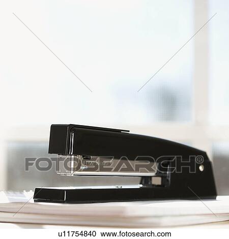Stock Image - Black stapler with window in background.. Fotosearch