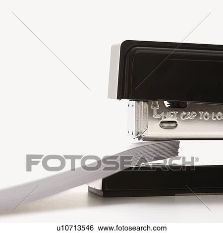 Stock Photograph - Close up of black stapler on white background stapling paper. Fotosearch