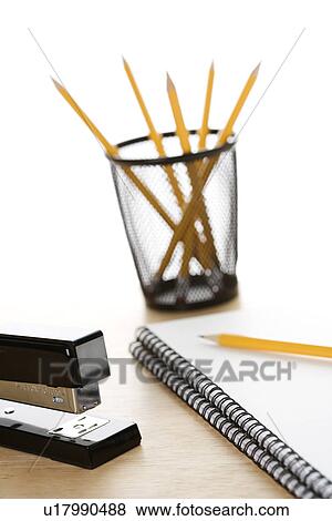 Stock Photo - Pencils, a stapler, and spiral bound notebooks arranged on a desk. Fotosearch