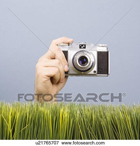 Male hand holding vintage camera with grass in foreground View Large Photo Image Stock Photo - Male hand holding vintage camera with grass in foreground. Fotosearch