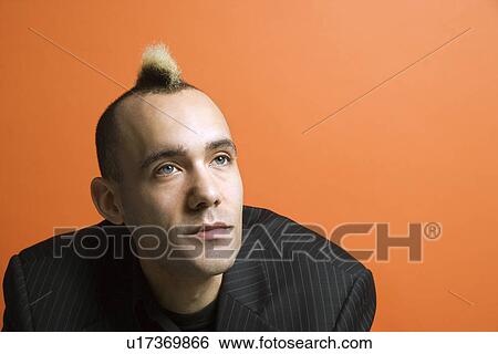 Stock Photograph - Caucasian man in suit with mohawk against orange background.. Fotosearch