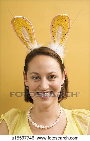 Stock Photograph - Caucasian mid adult woman wearing rabbit ears and looking at viewer.. Fotosearch