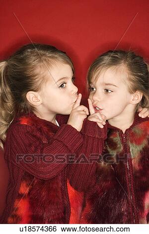 Stock Photograph - Twins with fingers up to lips. Fotosearch