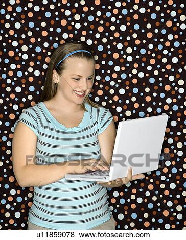 Stock Photo - Woman typing on laptop and smiling. Fotosearch