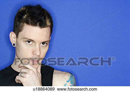 Stock Photo - Young adult Caucasian male pierced ear and tattoo.. Fotosearch