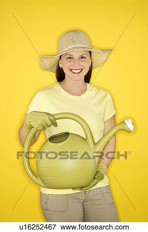 Young adult female Caucasian holding watering can wearing straw hat. View Large Photo Image Stock Photo - Young adult female Caucasian holding watering can wearing straw hat.. Fotosearch