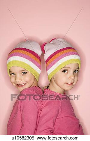 Stock Photography - Young female twin Caucasian children standing back to back.. Fotosearch