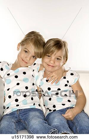 Stock Photo - Female children Caucasian twins sitting together on chair.. Fotosearch