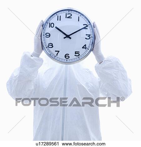 Man in biohazard suit holding clock in front of face standing against white background. View Large Photo Image Stock Image - Man in biohazard suit holding clock in front of face standing against white background.. Fotosearch