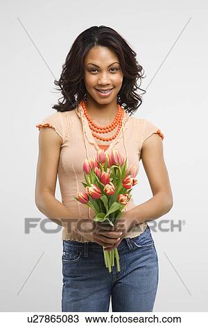 Studio shot of stylish woman holding bouquet of tulips smiling and looking at viewer. View Large Photo Image Stock Image - Studio shot of stylish woman holding bouquet of tulips smiling and looking at viewer. . Fotosearch