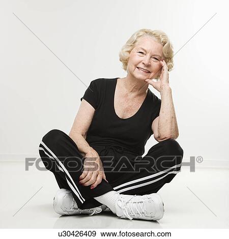 Stock Photo - Woman sitting on floor with legs crossed. Fotosearch