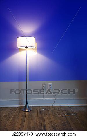 Stock Image - Blue projection light on wall with bright floor lamp.. Fotosearch
