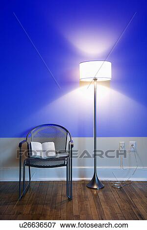 Stock Photo - Blue projection light on wall with bright floor lamp and open book on chair. Fotosearch