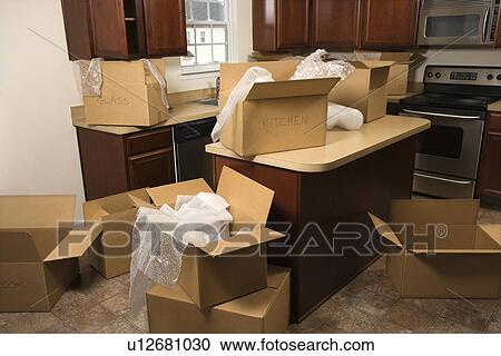 Stock Image - Cardboard moving boxes with bubble wrap in kitchen. Fotosearch