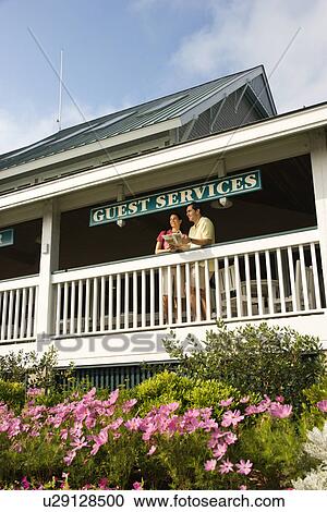 Stock Image - Mid-adult couple on deck of guest services at Bald Head Island, North Carolina.. Fotosearch