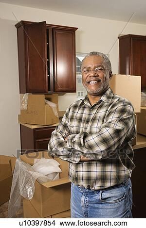 Portrait of middle-aged African-American male in kitchen with moving boxes. View Large Photo Image Picture - Portrait of middle-aged African-American male in kitchen with moving boxes.. Fotosearch