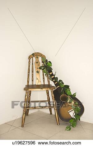 Still life of guitar with garland leaning against a chair. View Large Photo Image Stock Photograph - Still life of guitar with garland leaning against a chair.. Fotosearch
