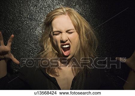 Picture - Dark portrait of sexy Caucasian mid-adult woman making fierce roaring expression.. Fotosearch