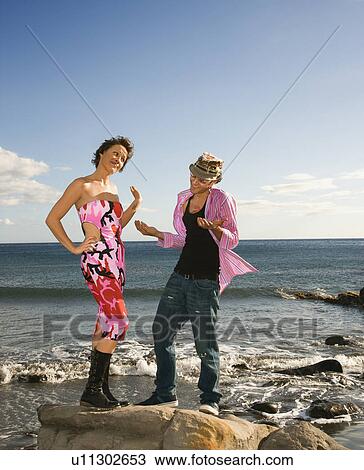 Stock Image - Male and female on a rocky shoreline. Fotosearch