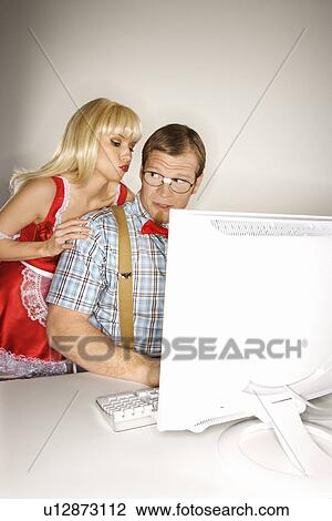 Stock Image - Man dressed like nerd at computer looking over shoulder at woman. Fotosearch