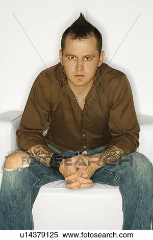 Stock Photography - Man with mohawk sitting with hands clasped together. Fotosearch