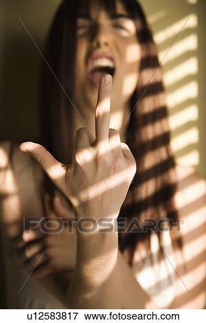 Stock Photo - Portrait of pretty Caucasian young woman giving middle finger with mouth open.. Fotosearch