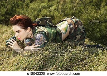 Tattooed woman in camouflage lying on grass looking through binoculars View Large Photo Image Stock Image - Tattooed woman in camouflage lying on grass looking through binoculars . Fotosearch