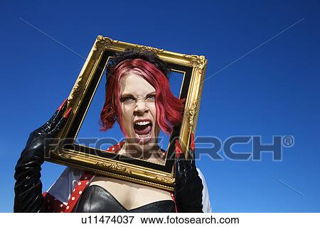 Stock Photo - Young adult Caucasian female holding empty frame around head.. Fotosearch