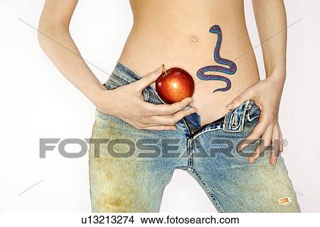 Picture - Portrait of attractive young woman holding apple by snake tattoo on stomach. Fotosearch