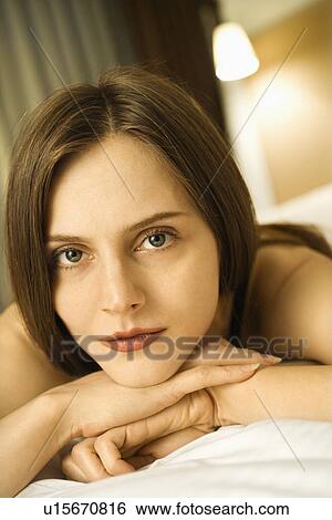 Stock Photograph - Portrait of Caucasian mid-adult woman looking at viewer with head resting on hands.. Fotosearch